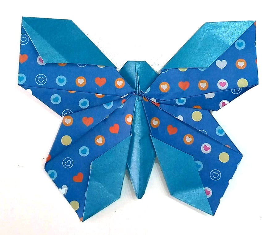 Blue origami bow with heart and circle patterns on a white background