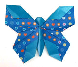 Blue origami bow with heart and circle patterns on a white background